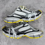 Gray and black chunky sneakers with white laces and yellow trim, unisex style.