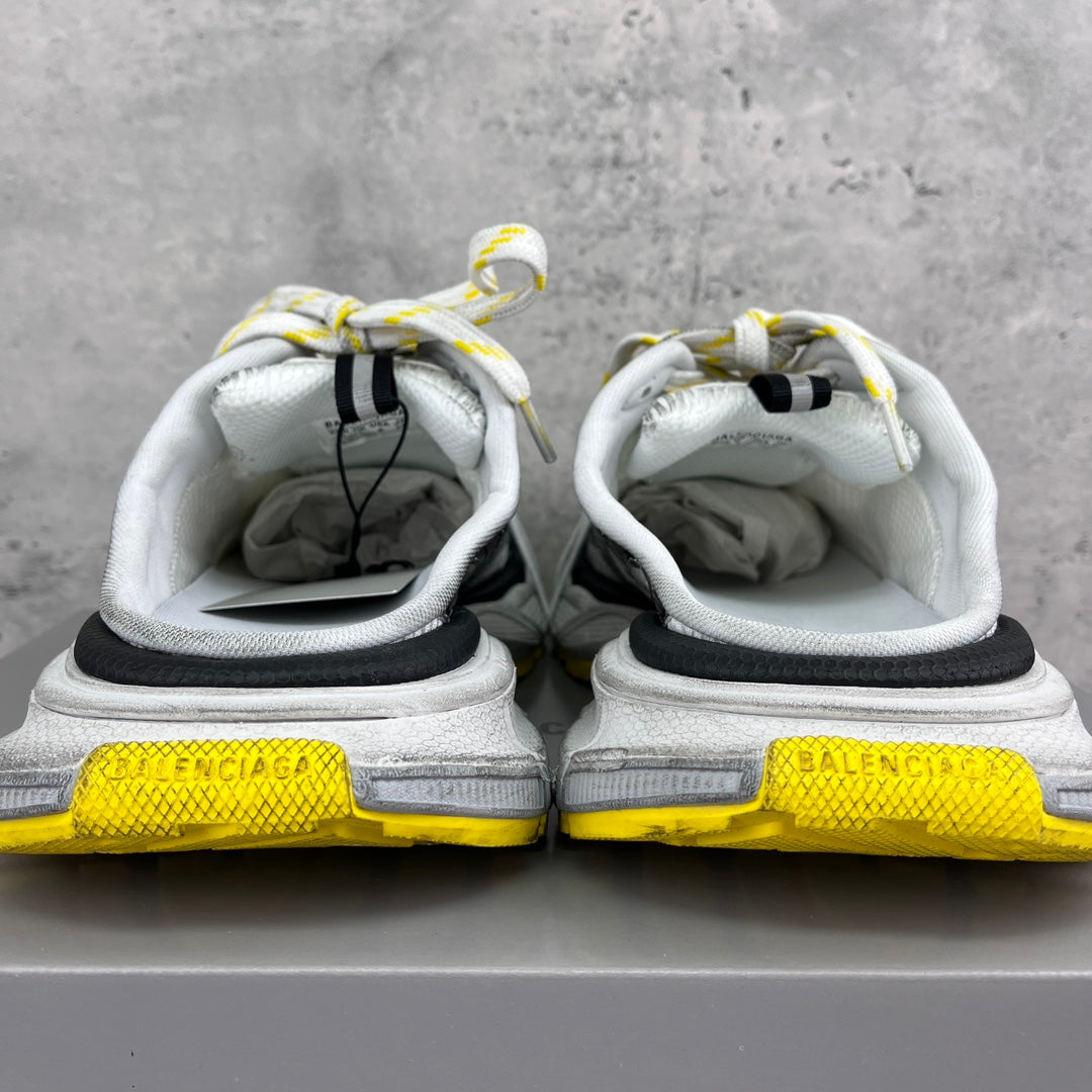 Back view of white and gray chunky sneakers with black heel inserts and yellow branding.