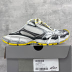 Gray and black chunky sneakers with mesh panels, white laces, yellow outsole trim.