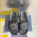 Black Dior slide sandals with fabric logo straps and thick molded footbeds