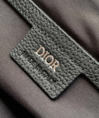 Dior bag logo patch close-up on dark leather with embroidered stitching.