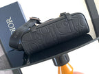 Dior bag in dark embossed leather, rolled top with hardware and side strap.