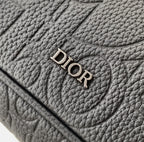 Dior bag close-up of “DIOR” logo on textured dark leather flap.
