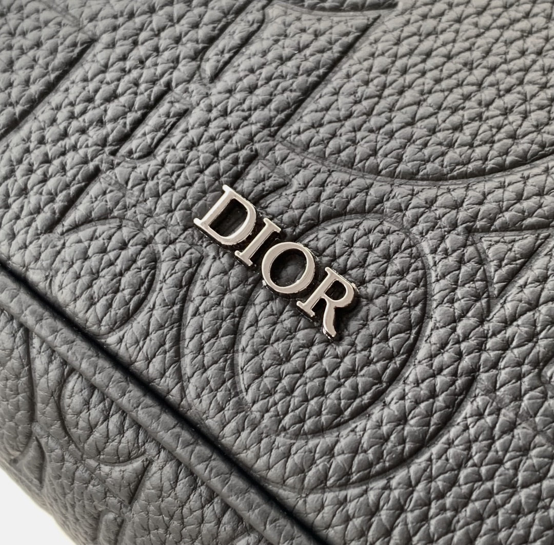 Dior bag close-up of “DIOR” logo on textured dark leather flap.