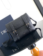 Dior bag in dark leather with embossed logo, front flap and gold-tone buckles.