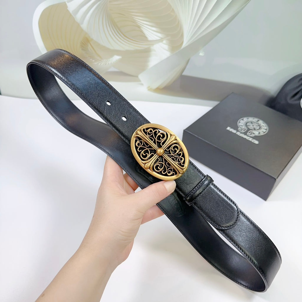 Black leather belt held up by hand, showing the gold decorative buckle center.
