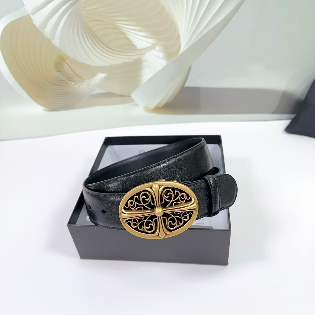 Black leather belt with ornate gold buckle, displayed in a box.