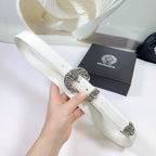 White leather belt close-up with filigree silver buckle and embossed metal detail
