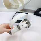 White leather belt held up showing silver filigree buckle and matching end caps
