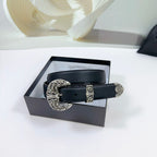Dark leather belt with ornate silver buckle, resting on a gift box