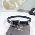 Leather belt with dark strap and ornate silver buckle, shown looped on a box