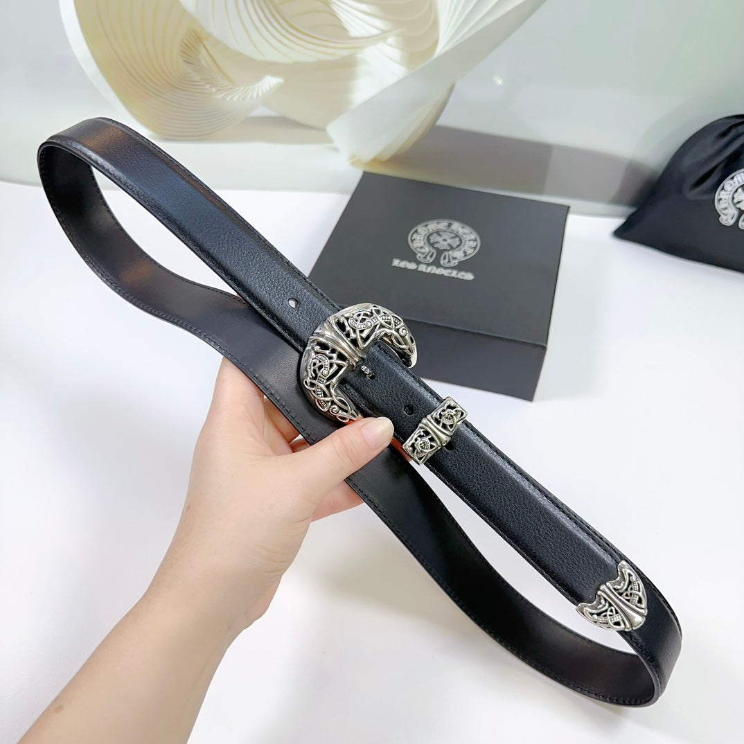 Black leather belt held in hand, ornate silver buckle with engraved pattern