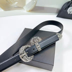 Black leather belt buckle close-up with engraved silver emblem and keeper