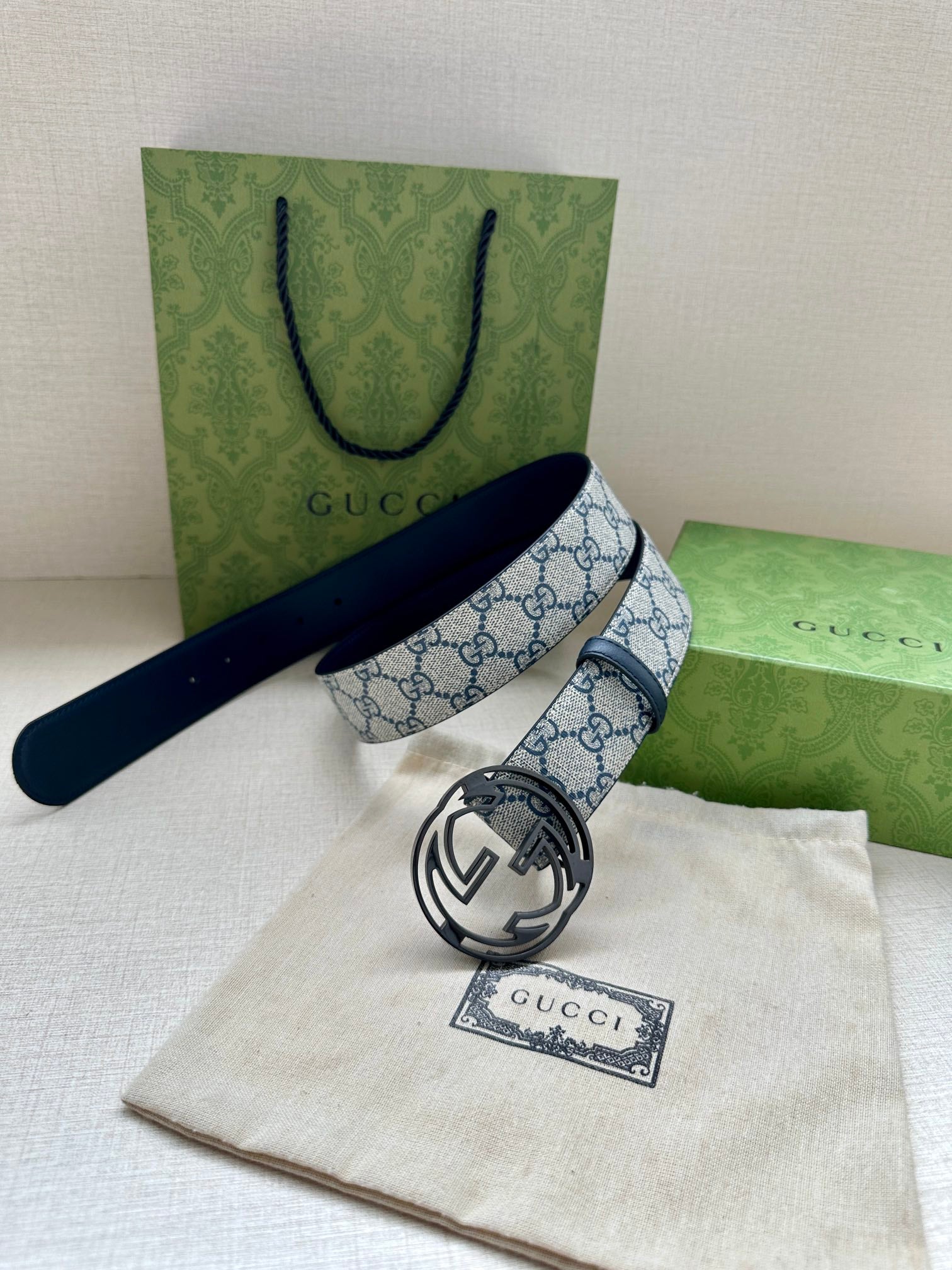 Gucci belt with blue GG canvas strap and silver interlocking G buckle on dark blue backing