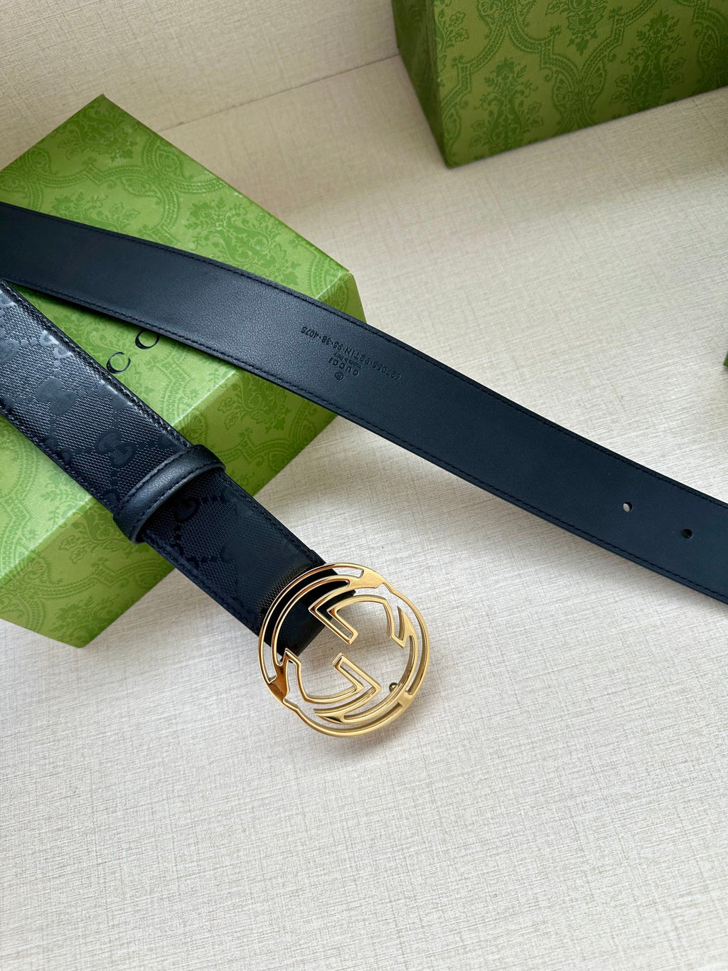Gucci belt with dark blue strap and gold interlocking G buckle, laid out flat.