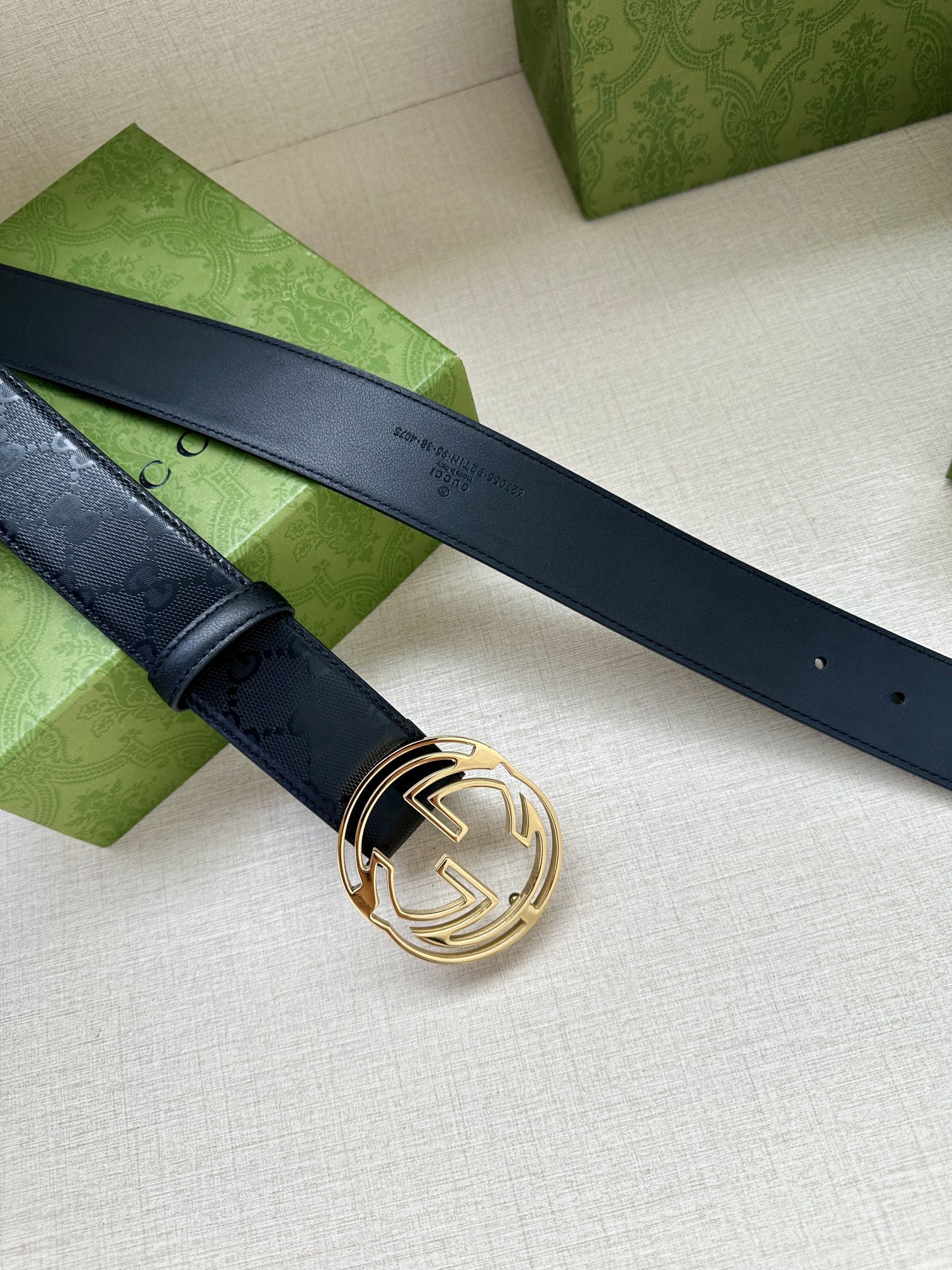 Gucci belt with dark blue strap and gold interlocking G buckle, laid out flat.