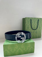 Gucci belt with navy strap and silver interlocking G buckle, resting upright.