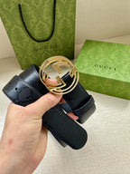 Gucci belt with dark blue strap and gold interlocking G buckle, held in hand.