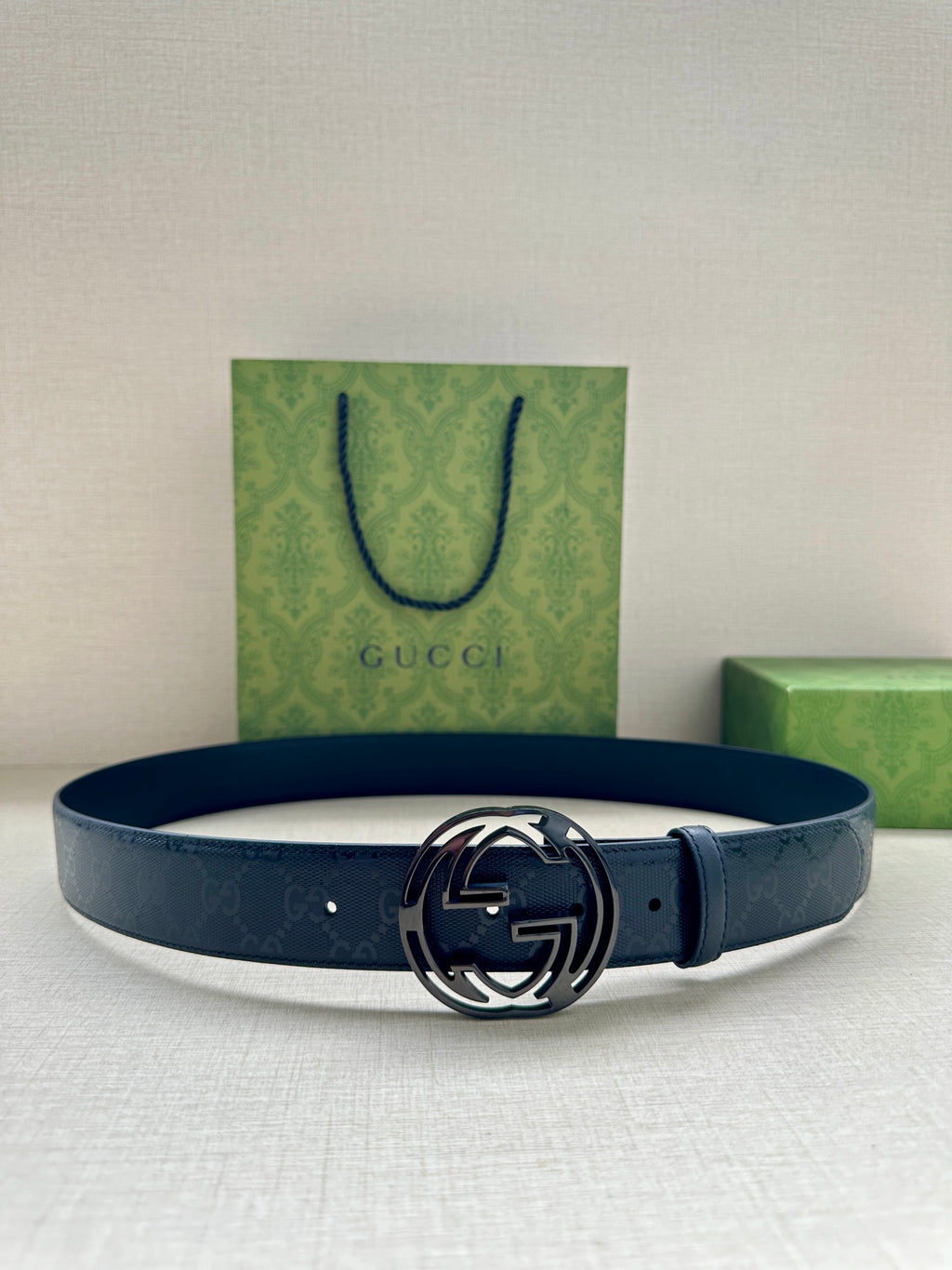Gucci belt in dark navy blue with silver interlocking G buckle, laid flat.