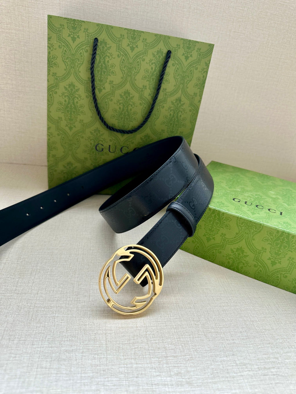 Gucci belt with dark navy strap and gold interlocking G buckle, angled view.