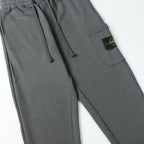 Charcoal gray drawstring pants with side cargo pocket and Stone Island patch