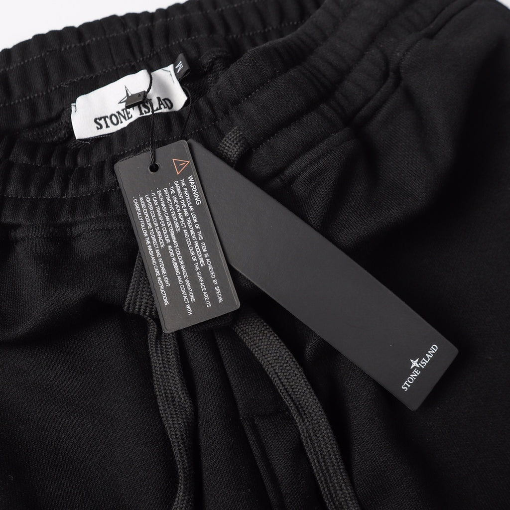 Stone Island black jogger pants with care label and hanging brand tag
