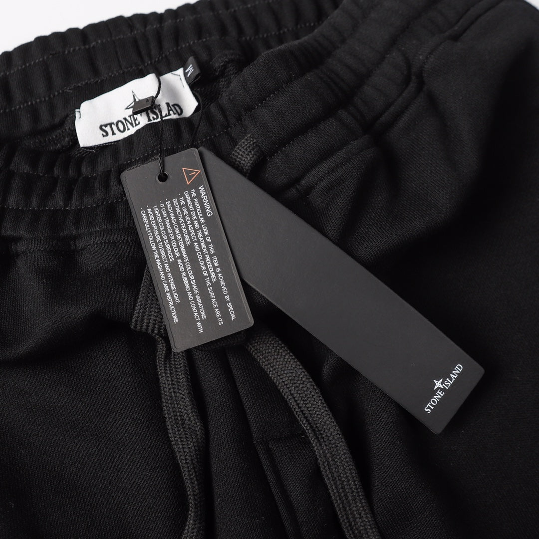 Stone Island black jogger pants with care label and hanging brand tag