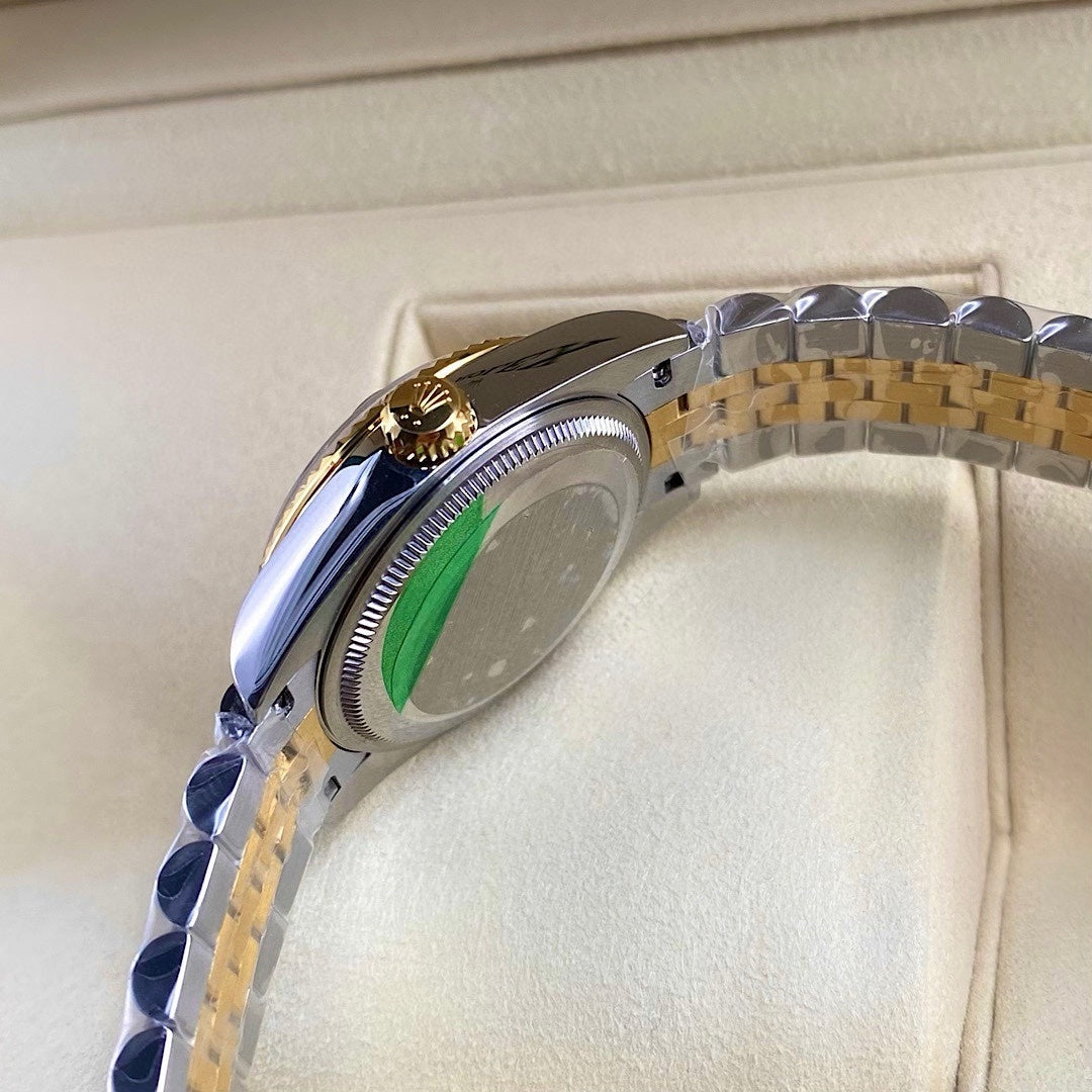 Rolex watch side view with gold accents and polished silver case, green dial visible