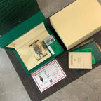 Rolex watch with green dial and included papers, booklet, and certificate cards
