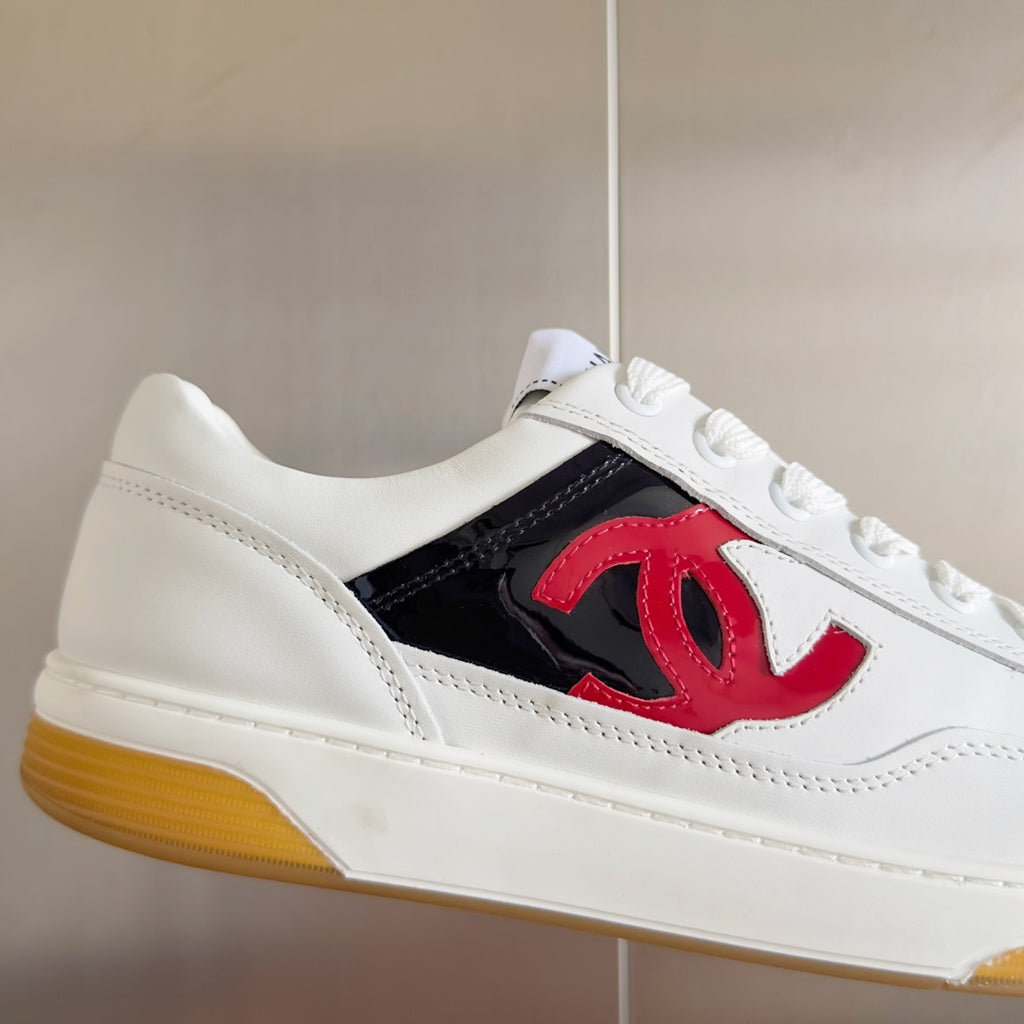 White low-top sneakers with red CC logo patch, lace-up front, gum yellow outsole