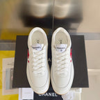 Two white low-top sneakers front view, lace-up design with red CC logo, gum sole