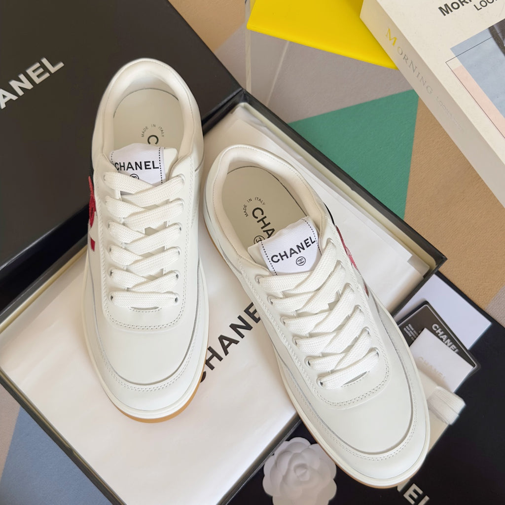 Pair of white low-top sneakers with red CC logo, lace-up design, gum yellow sole