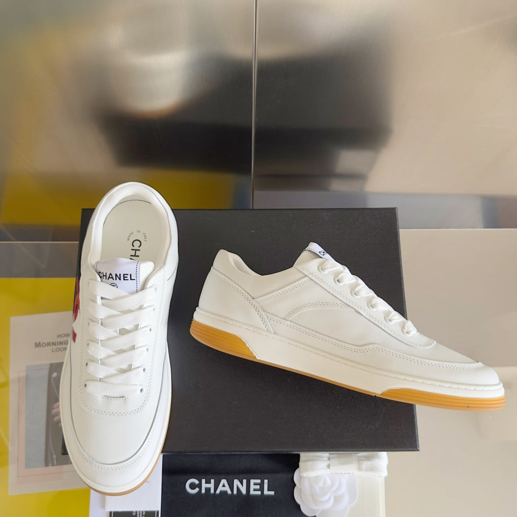 White low-top sneakers with red CC logo, side view, gum yellow sole
