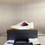 White low-top sneakers with red CC logo on front, on dark shoe box