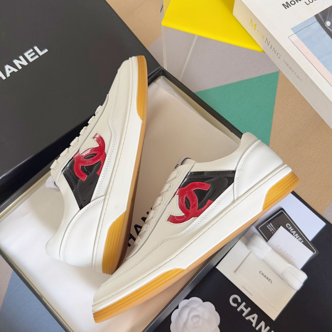 White low-top sneakers with red CC logo and gum sole on shoe boxes
