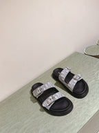 Dior slide sandals pair with light gray monogram straps and black rubber soles
