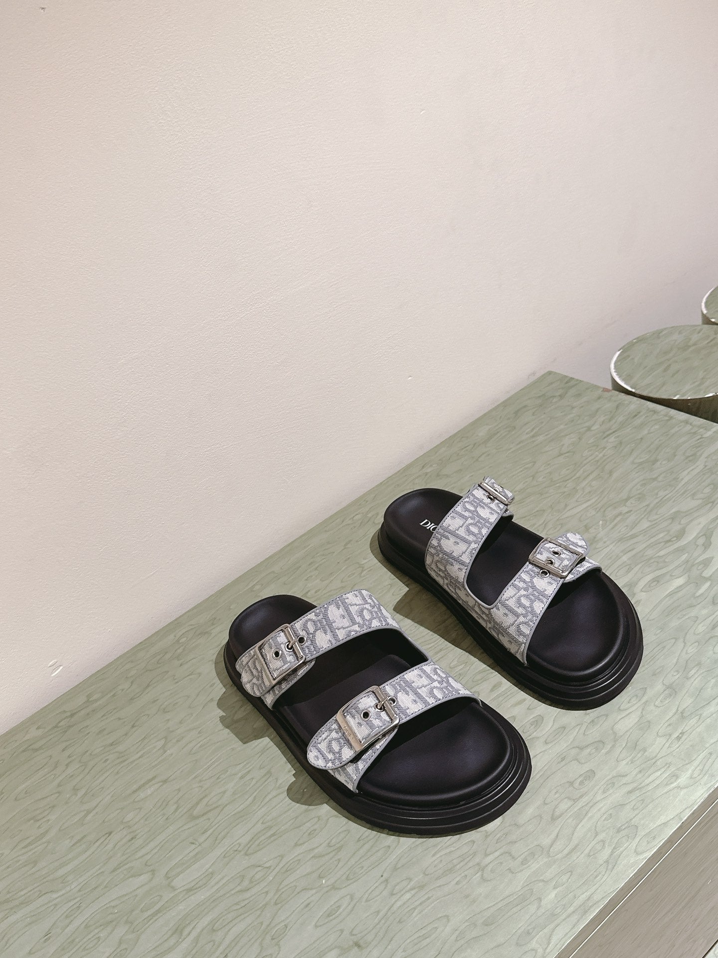 Dior slide sandals pair with light gray monogram straps and black rubber soles