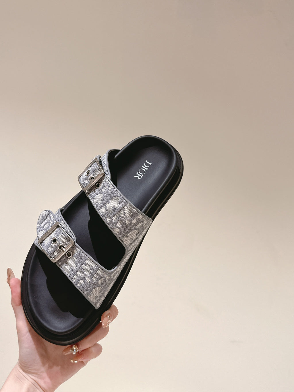 Dior slide sandals held up, monogram straps with two buckles over black footbeds