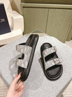 Dior slide sandals showing monogram straps and buckles over black footbeds