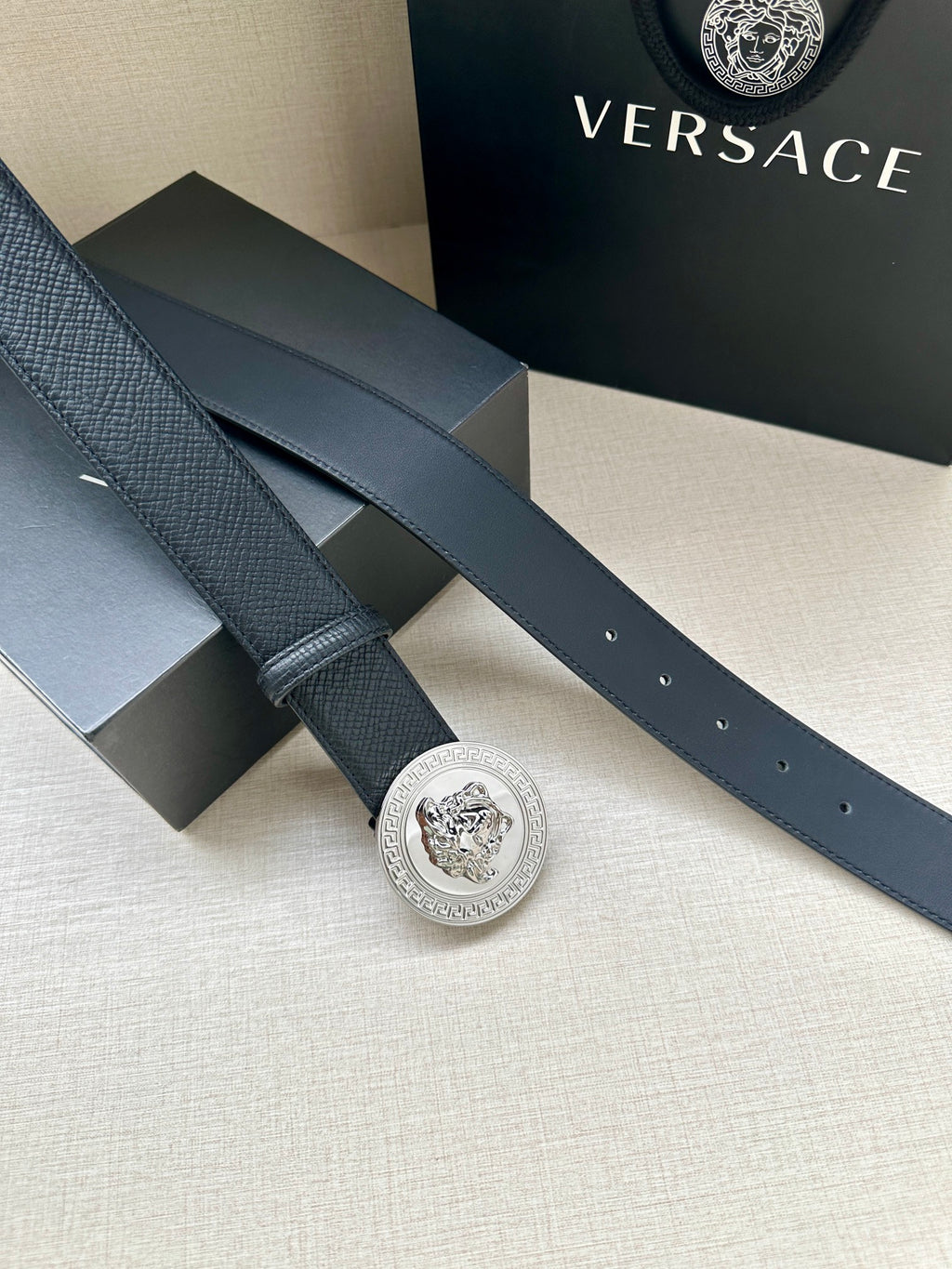 Dark leather belt with long strap and round silver Medusa buckle