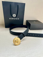 Dark leather belt with round gold Medusa buckle and matching keeper strap