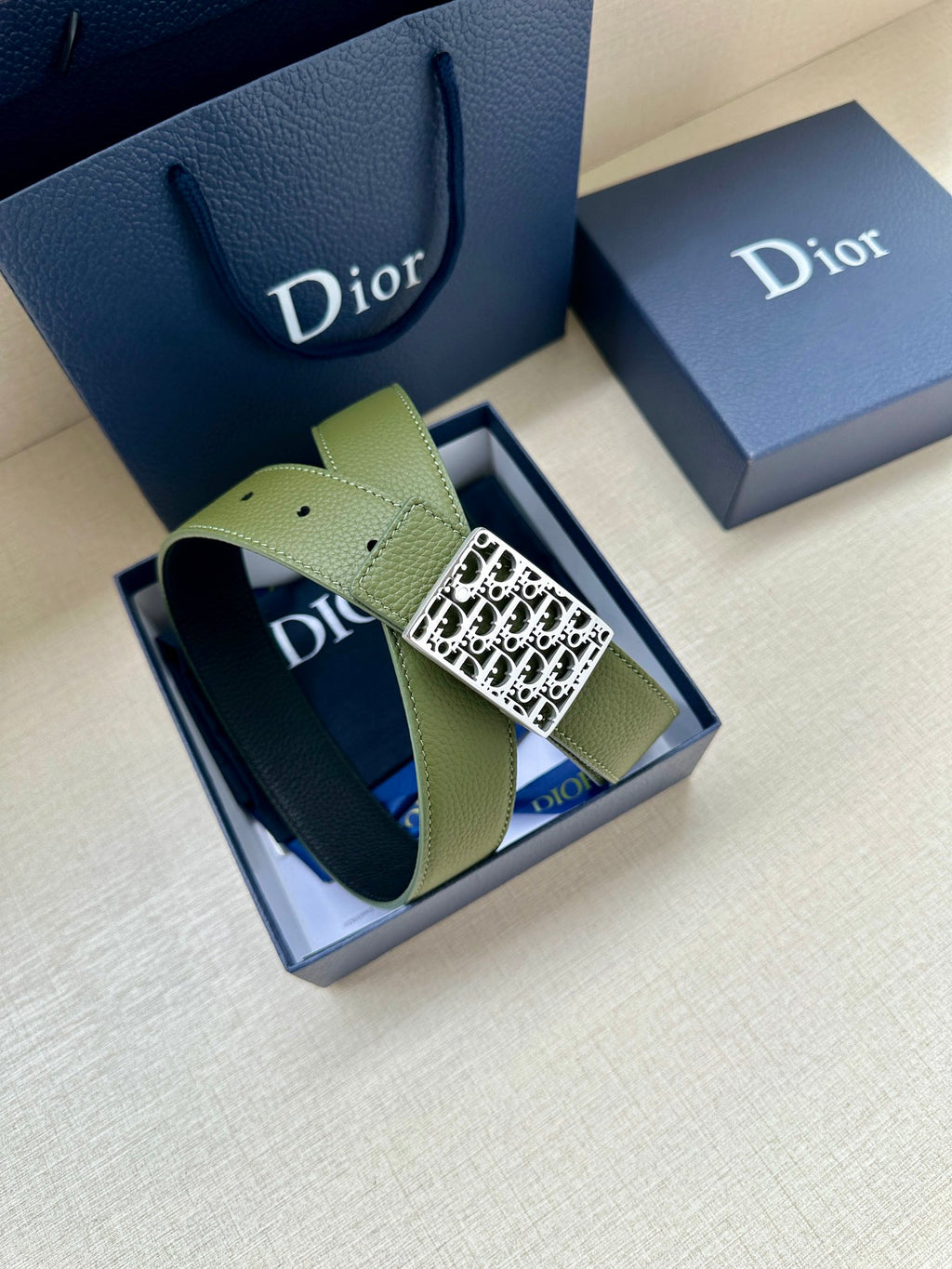 Dior belt display: olive green leather strap with gold-tone Dior monogram buckle