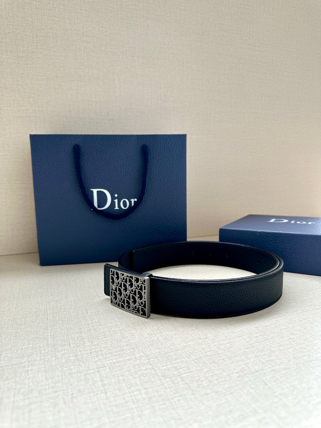 Dior leather belt with square monogram buckle on dark strap.