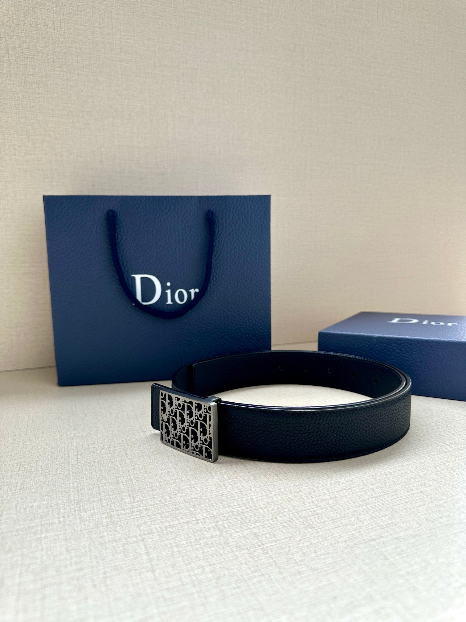 Dior leather belt with square monogram buckle on dark strap.