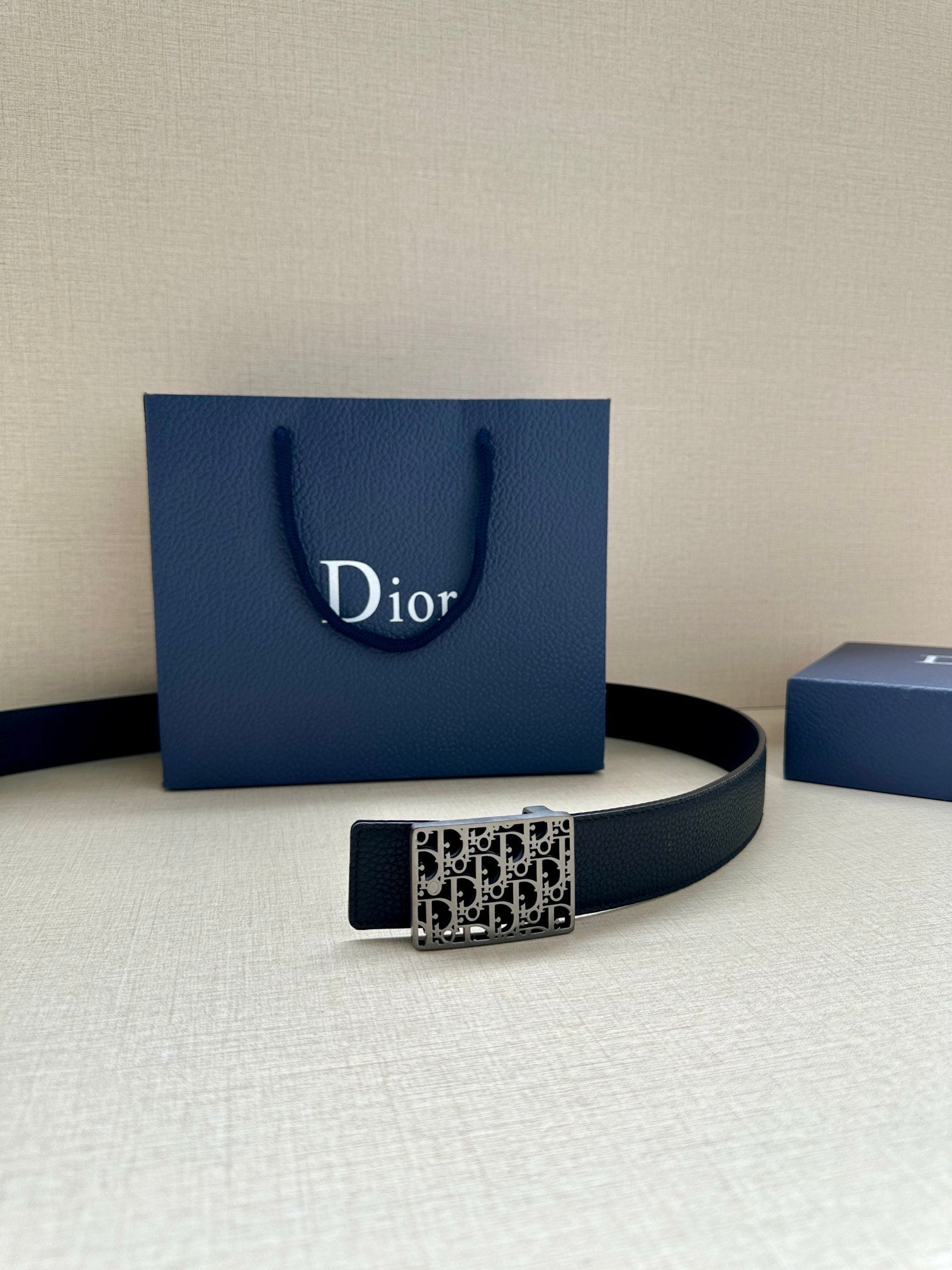 Dior leather belt with square monogram buckle on dark strap.