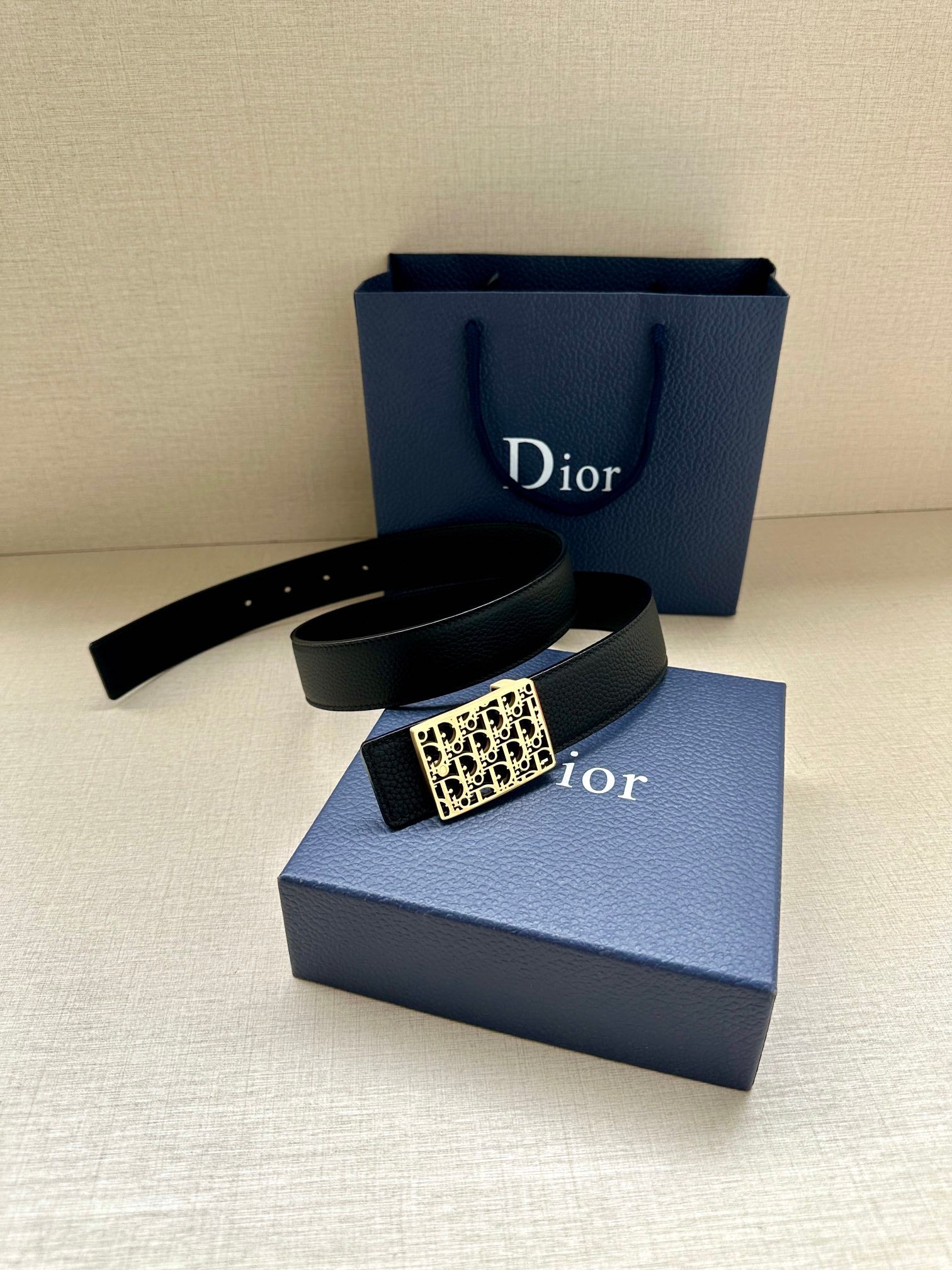 Dior leather belt with gold-toned square monogram buckle, folded on box.