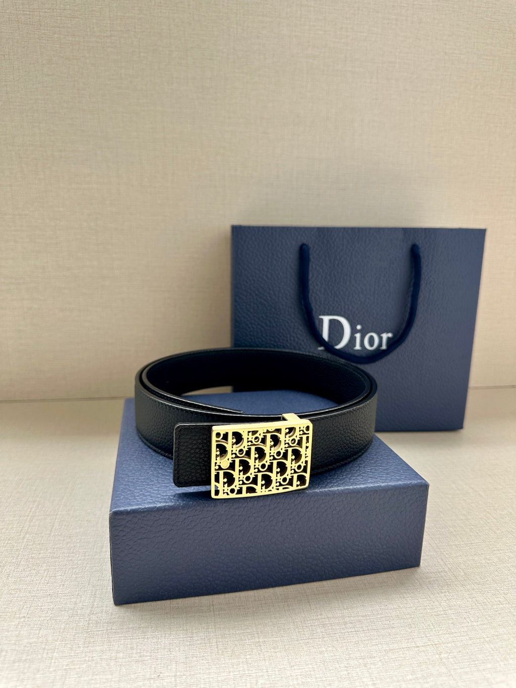 Dior leather belt with square monogram buckle on a dark strap.