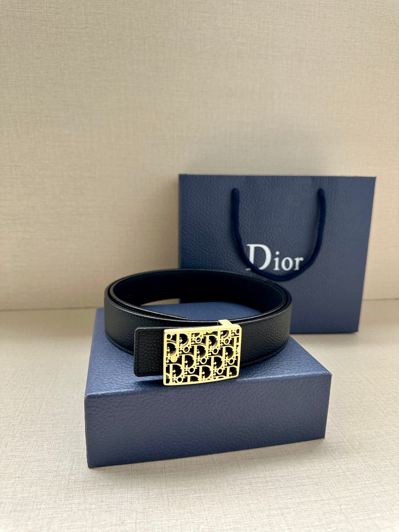 Dior leather belt with square monogram buckle on a dark strap.
