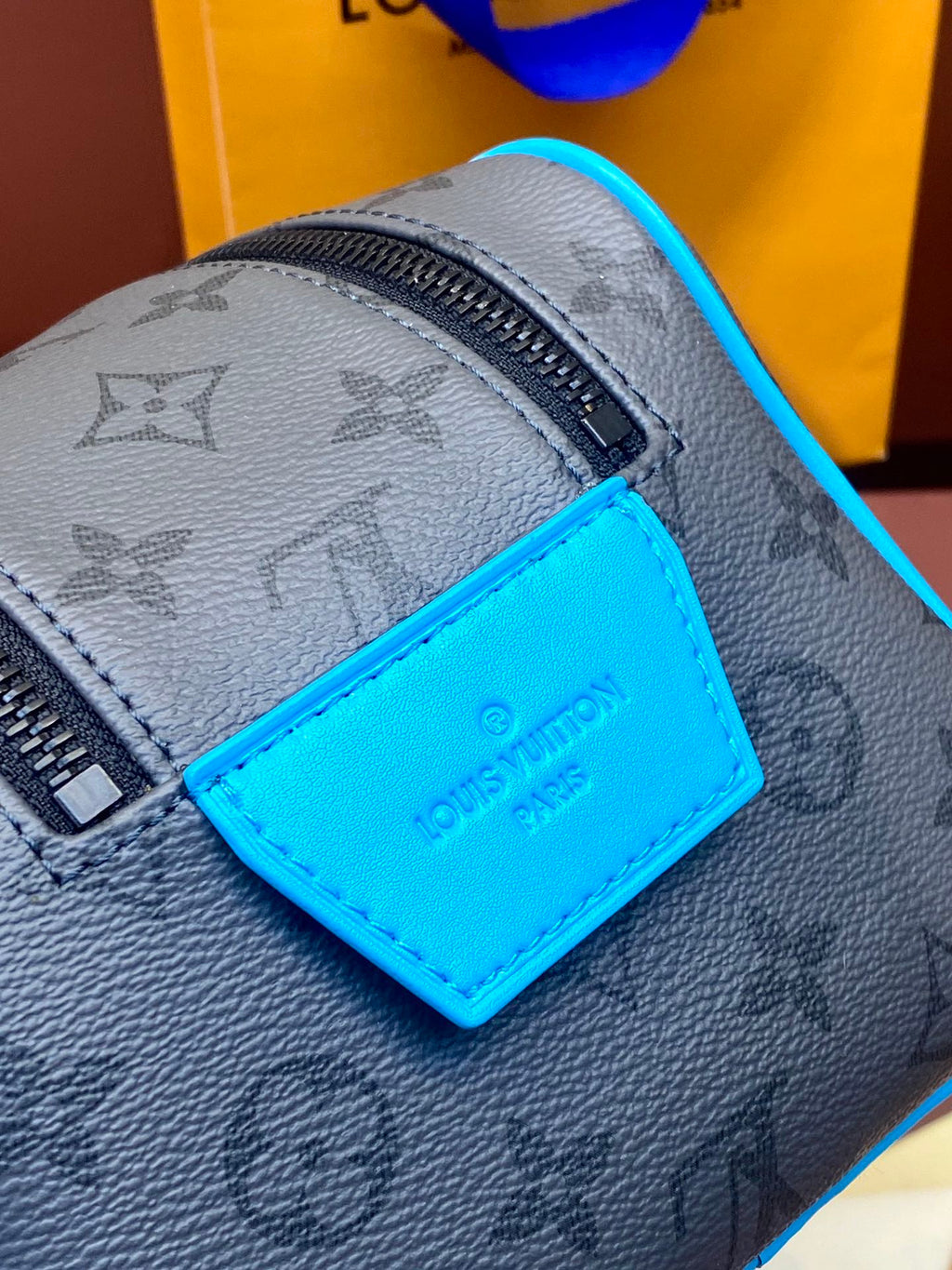 Louis Vuitton monogram bag close-up with blue leather logo label and zipper
