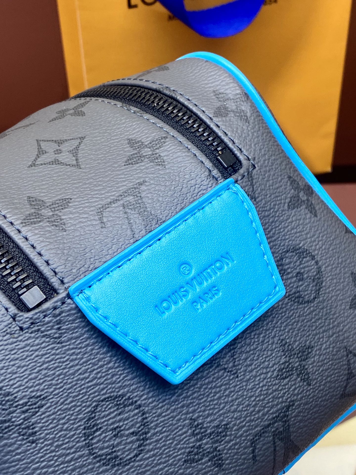 Louis Vuitton monogram bag close-up with blue leather logo label and zipper
